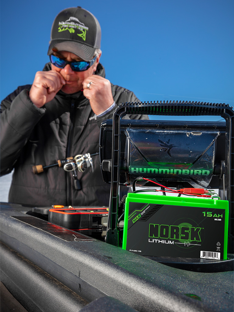 Ice Fisherman tying a bait with a Norsk Lithium Battery Powering his fish finder
