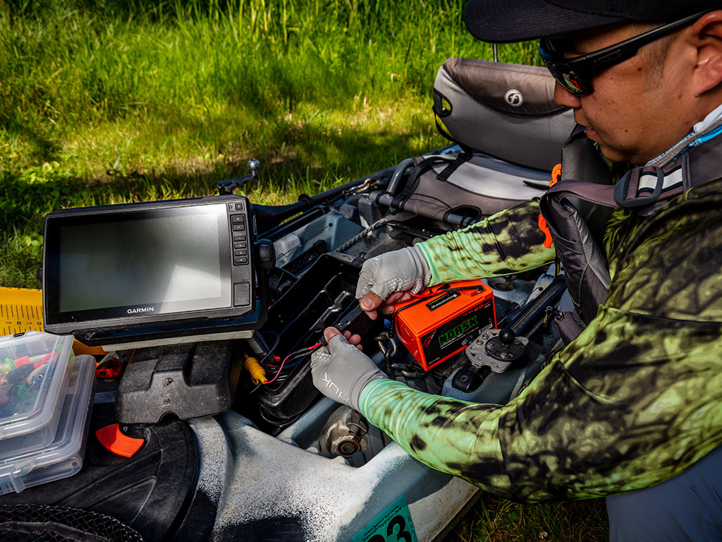 Kayak fisherman connecting a Norsk lithium battery to power his electronics 2