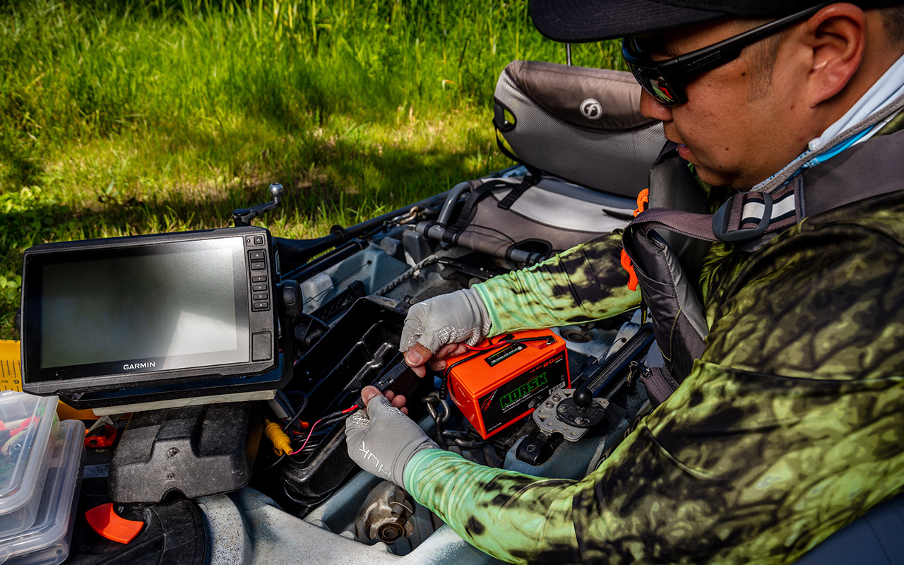 Kayak fisherman connecting a Norsk lithium battery to power his electronics 3