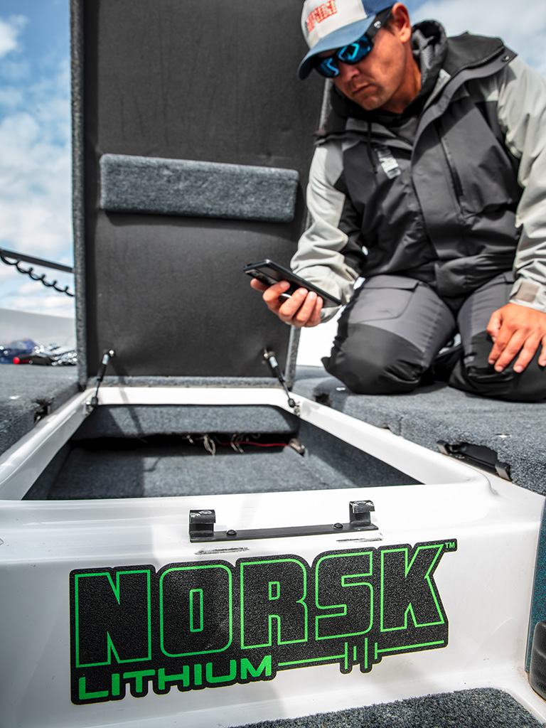 Fisherman holding his phone connecting to a Norsk Lithium Battery with the Norsk Lithium Guardian App 768X1024