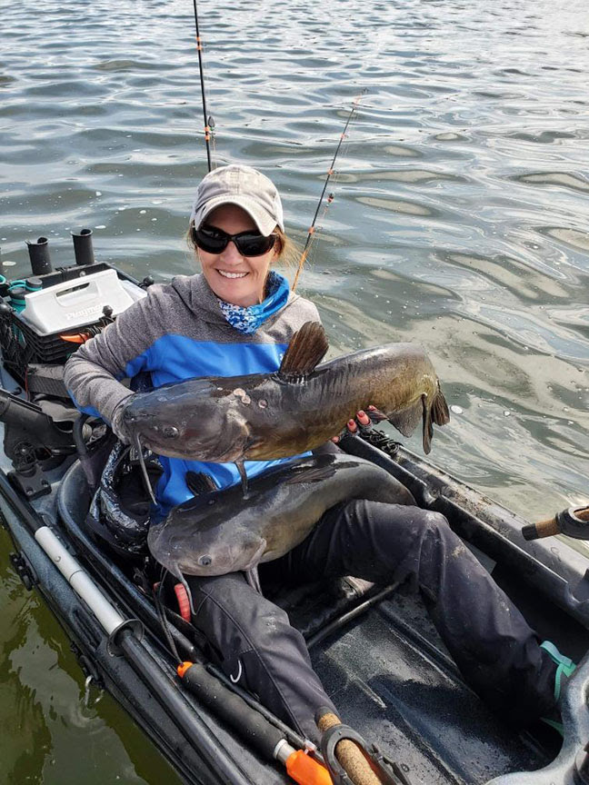 NORSK Lithium Kayak Pro Amy Hansen holding two Catfish
