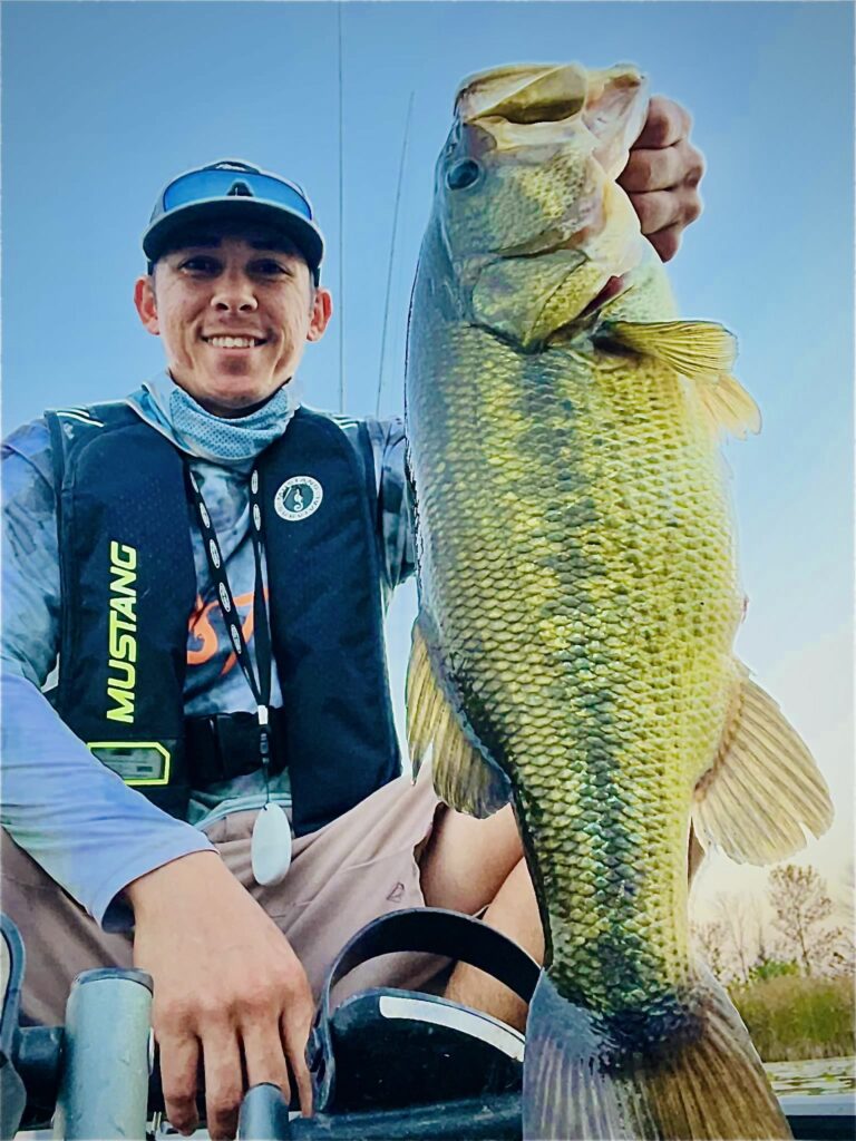 Daniel Zimmerschied NOrsk Pro Staff kayak angler holding bass using Norsk Lithium battery to power his trolling motor 2