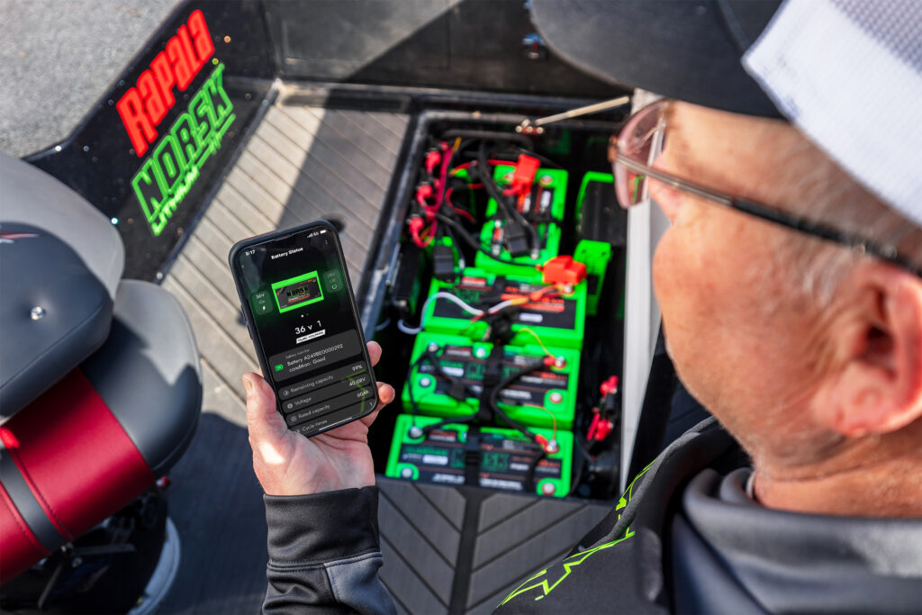Tim Winterhalter Over the shoulder of angler checking his Norsk Lithium marine batteries on the Norsk Guardian App in his fishing boat