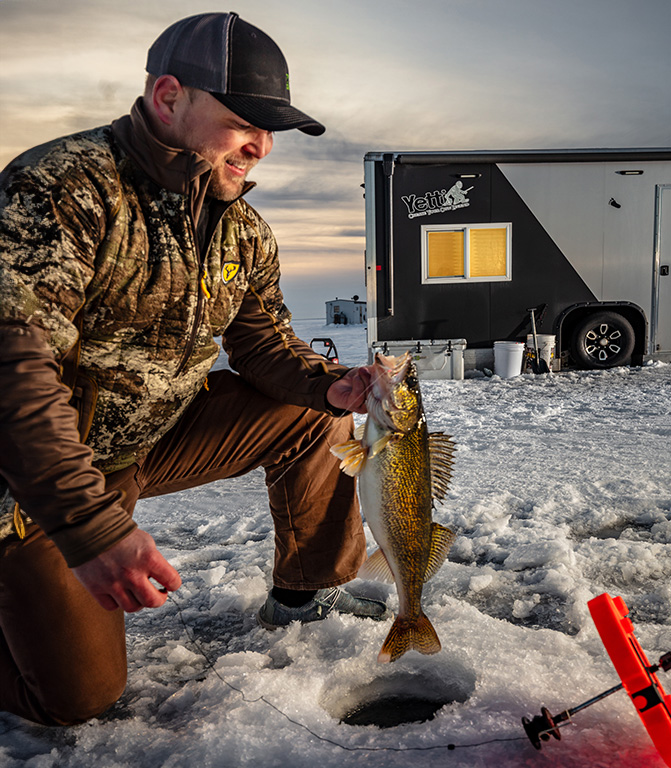 Angler catching a walleye on a tip up outside of his Yetti Wheelhouse powered by Norsk Lithium Batteries 671X768