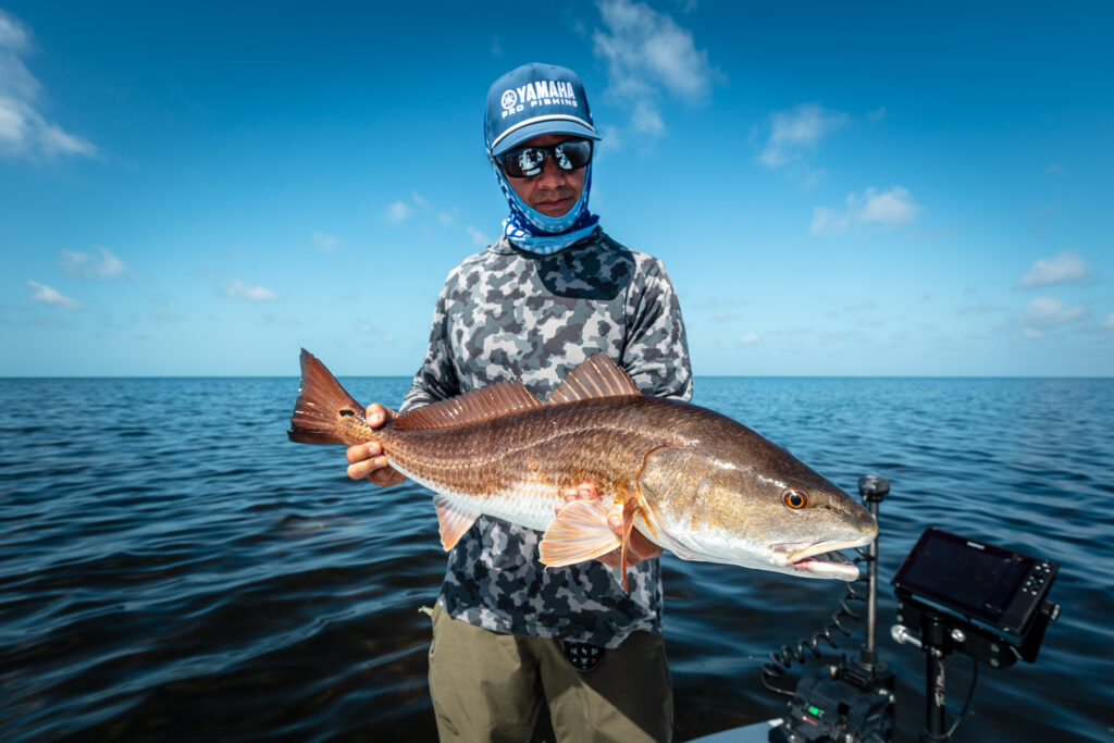 Yamaha Pro Fishing Team Member Chris Cenci holding a red fish on the Florida flats Web