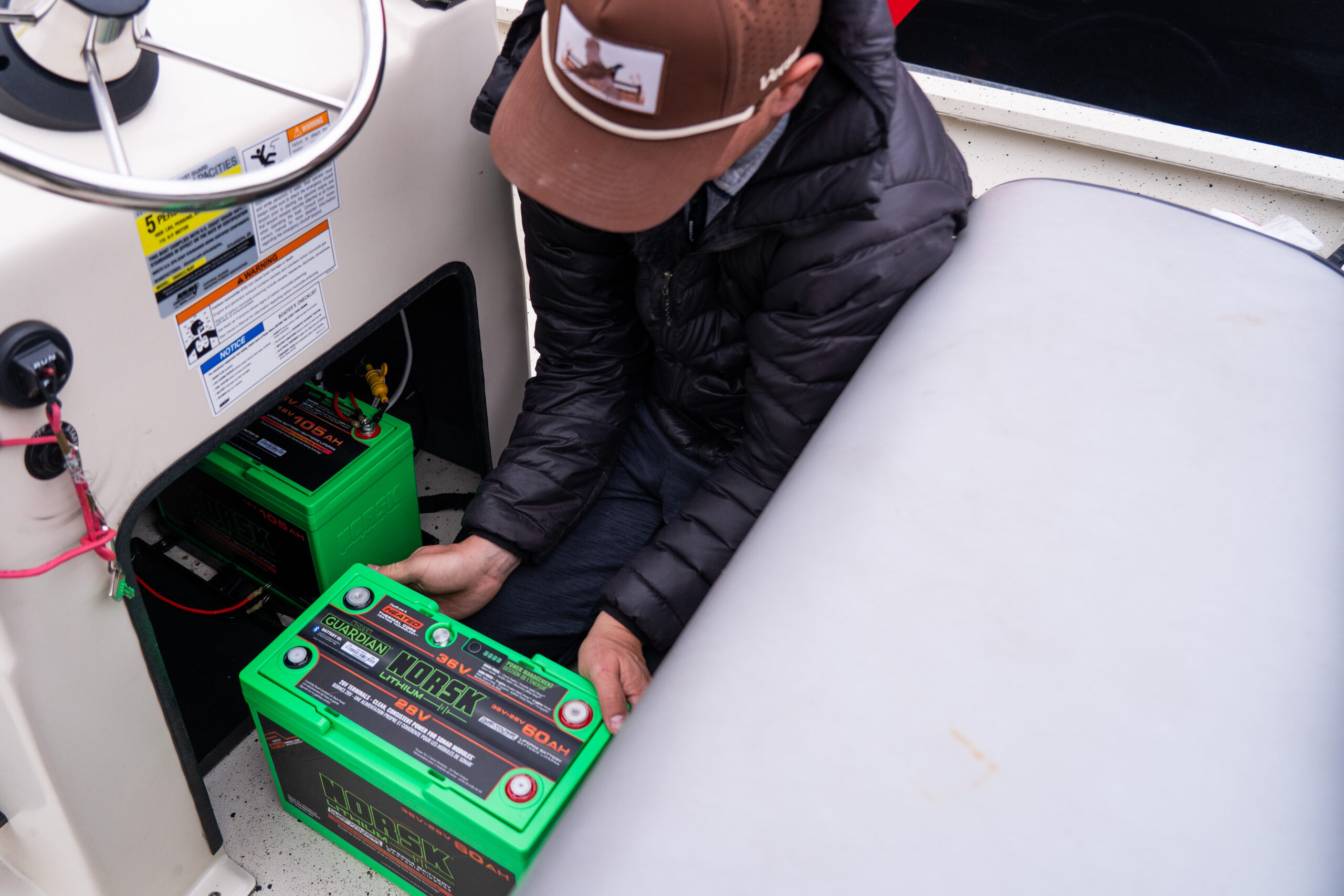 Angler installing a Norsk Lithium 36V battery in a boat battery tray